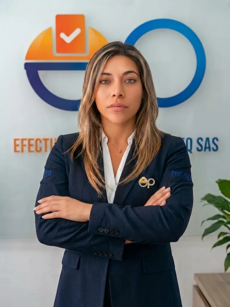 Marcela Irreño C., de pie y con los brazos cruzados en una oficina, con el logotipo de Efectuando Procesos en la pared del fondo
